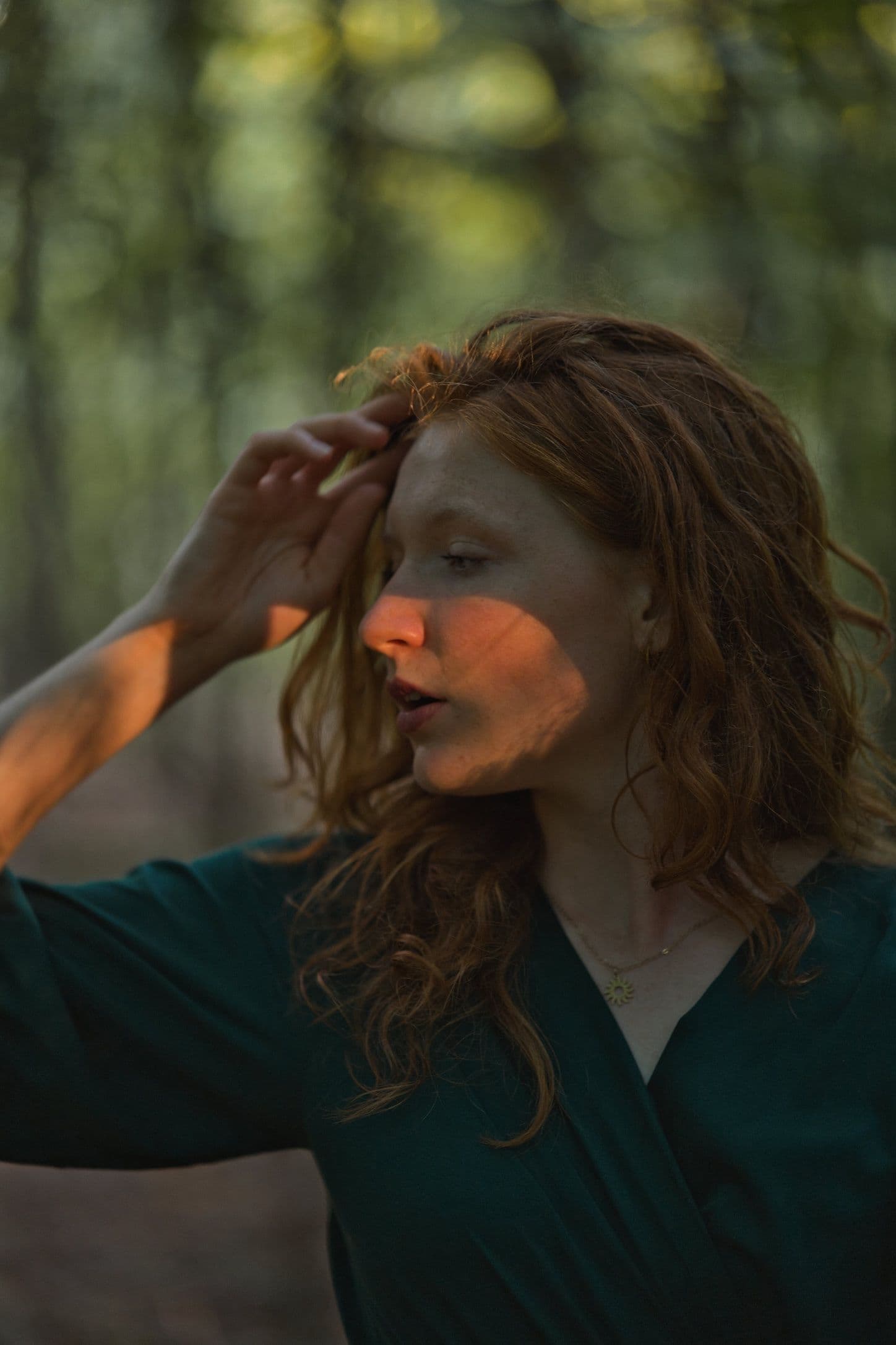 Portrait of a woman in a forest, lit by warm sunlight